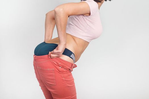 Close-up of woman body pulls on her summer pants. Diet, overweight, obesity concept.