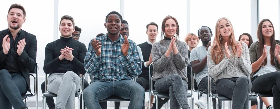 smiling young people applauding at a business seminar. business and education