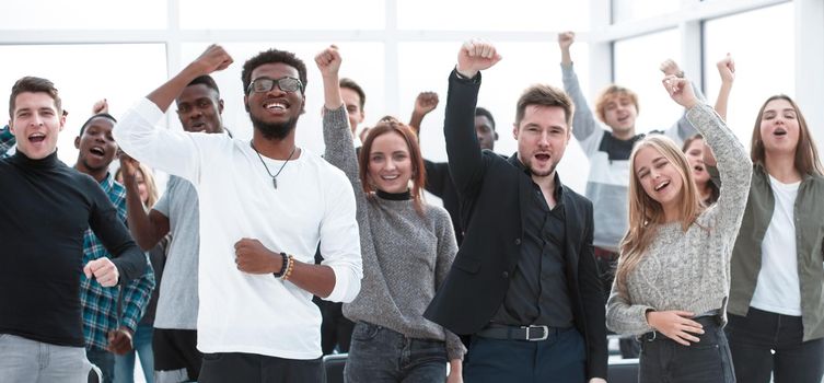 group of happy young people standing with their hands up. concept of success