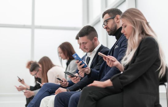 group of young business people with smartphones sitting in a row. photo with copy space
