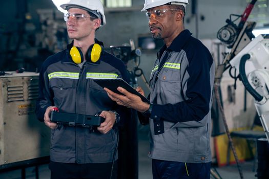 Group of factory job workers using adept machine equipment in a workshop . Industry manufacturing and engineering technology concept .