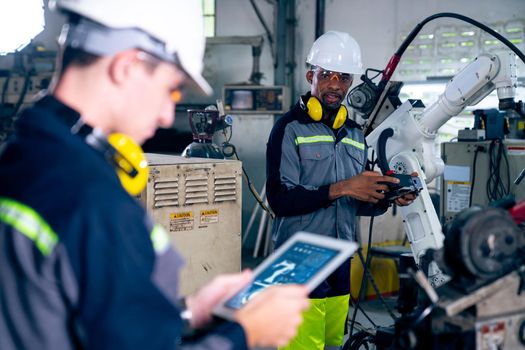 Factory workers working with adept robotic arm in a workshop . Industry robot programming software for automated manufacturing technology .