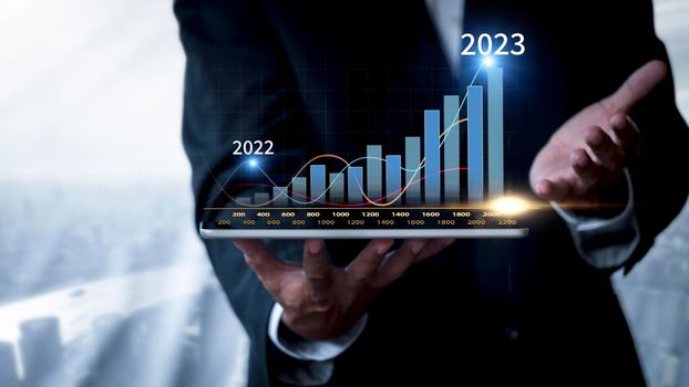Hand of businessman holding tablet analysis stock market graph growth and increase of chart positive indicators. Hand holding tablet show stock chart on light gray background. copy space banner
