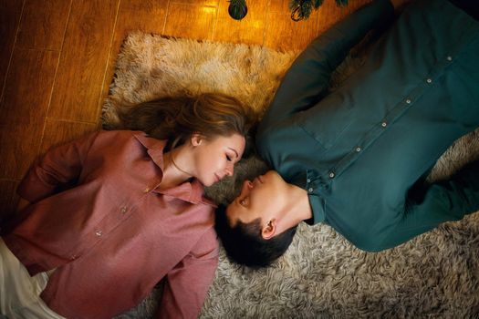 Beautiful middle aged caucasian couple lies on the cozy carpet. top view. film grain effect