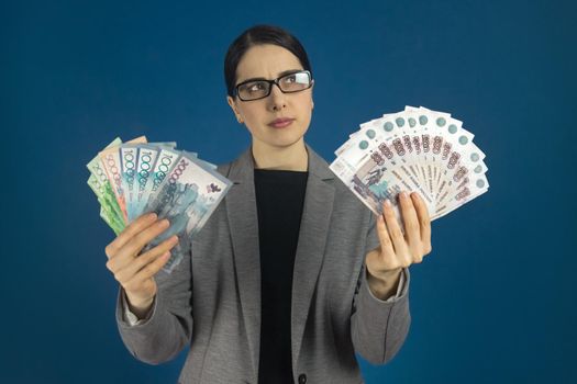 Thinking woman with a pack of Kazakhstan tenge and Russian rubles in her hand. Immigration concept. Selective focus.