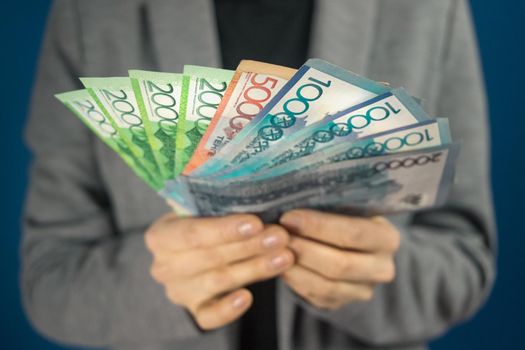 Qazaqstan money tenge in hands against the background of a woman in gray jacket.