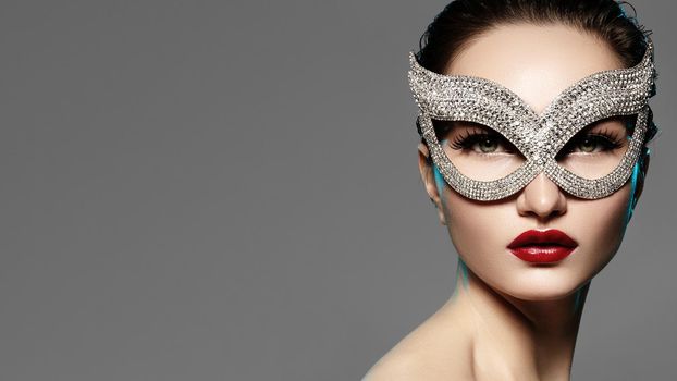 Beautiful Model with Fashion Lips Makeup Wearing Bright Brilliant Mask. Masquerade Style Woman. Holiday Celebration Look. Horizontal Beauty Photo