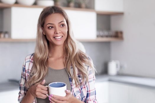 close up. cute young woman with mug standing in kitchen
