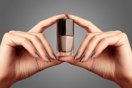 Manicured nails with beige nail polish. Manicure with natural nailpolish. Fashion manicure. Shiny gel lacquer in bottle. Trend color of the 2021 year