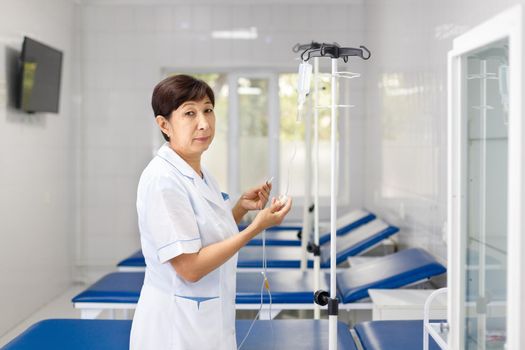 Central Asian senior nurse ready to put saline drip.