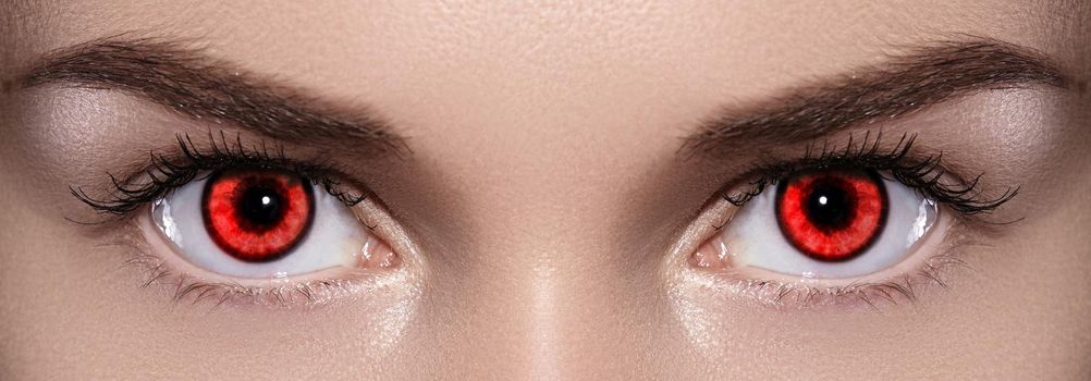 Close-up of Woman Eyes. Halloween Makeup. Devil, Vampire or Monster Eye Lens. Luminous Red Eyes. Closeup Shot