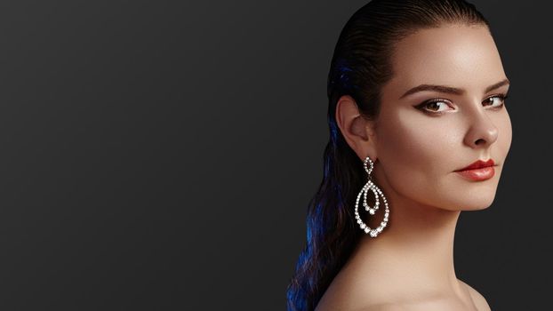 Beautiful Woman wearing Luxury Fashion Earrings. Diamond Shiny Jewelry with Brilliants. Sexy Retro Style Portrait. Model with Glamour Accessories Jewelery, Fashion Makeup and Wet Hair