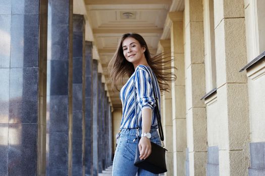 Happy Woman. Street Style Outdoors Portrait of Beautiful Girl. Young Woman Smiling. She wearing Print Shirt, Blue Jeans and Black Bag. Happy Lifestyle shoot