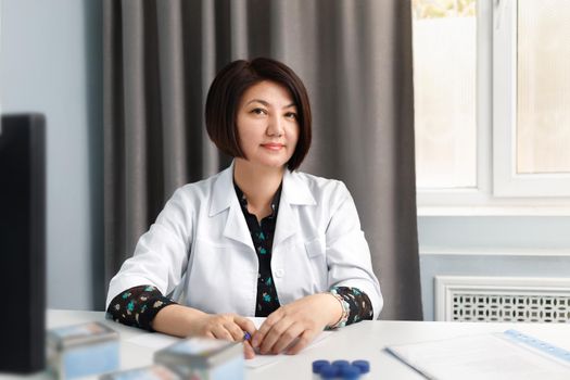 Portrait of a female doctor in an office at a table in a Kazakhstan clinic.