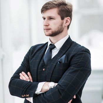 newcomer businessman in a business suit stands near the window, hands folded in front of him .the photo has a empty space for your text