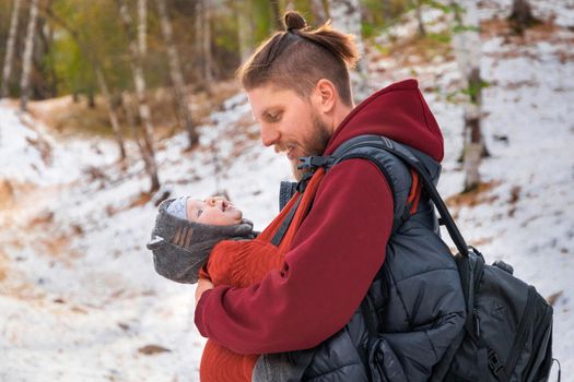 Babywearing young father with his infant baby in sling outdoor.