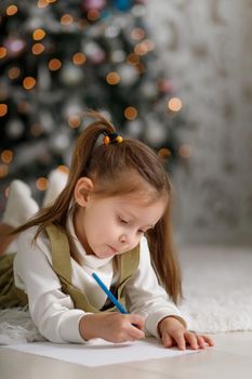 Cute little girl with ponytails is writing a letter to santa claus, vertical copy space.