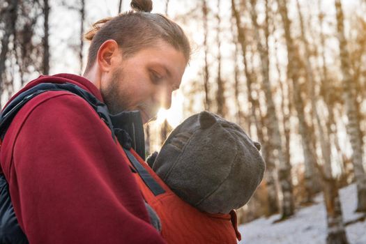 Close-up portrait of caucasian young father with his baby walking in the forest.