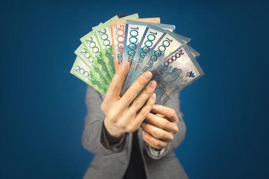 Kazakhstan various denominations money tenge in hands against the background of a woman in gray jacket.