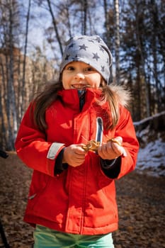 Joyful preschool aged girl in red jacket in deep autumn forest.