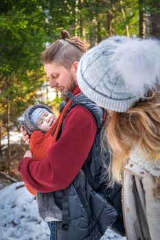 Portrait of young babywearing family with his son in baby sling, winter travel outdoor.