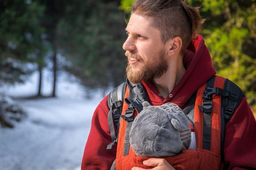 Portrait of adorable bearded babywearing father with his son in baby carrier winter outdoor.