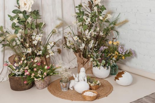 Interior floral Easter composition. Figurines of Easter bunnies and a large eggshell. The concept of home decoration for the Happy Easter holiday