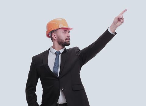 in full growth. young businessman in helmet pointing to copy space. isolated on white