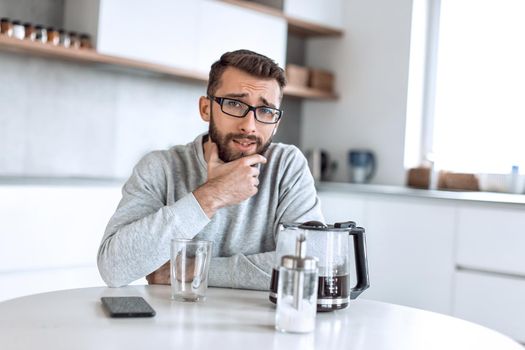 close up. attractive man sitting at the kitchen table in the morning