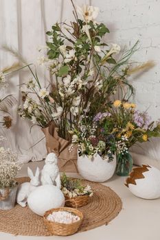 Interior floral Easter composition. Figurines of Easter bunnies and a large eggshell. The concept of home decoration for the Happy Easter holiday