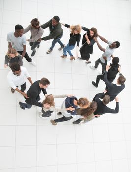 Large group of people seen from above, gathered in the shape of a circle, standing on a concrete backgroun