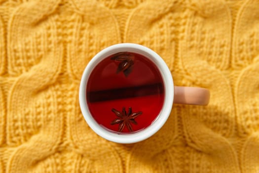 Karkade tea in an orange cup on an orange knitted background. The concept of the autumn season, natural colors. Red fruit tea.