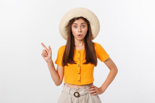 Teenager girl on summer vacation surprised and pointing finger on copy space over isolated white background