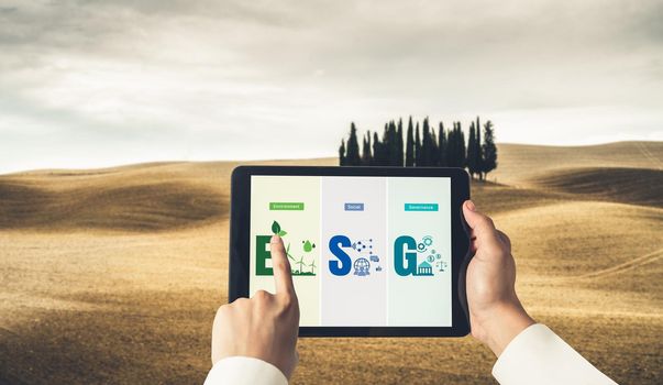 Green business transformation for environment saving and ESG business concept. Businessman using tablet to set corporate goal toward environmental friendly management and alternative clean energy use.