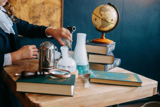 Schoolgirl perform chemical experiments. Flasks with solutions and chemical formulas on the blackboard in the school classroom. Back to school. School and preschool education.