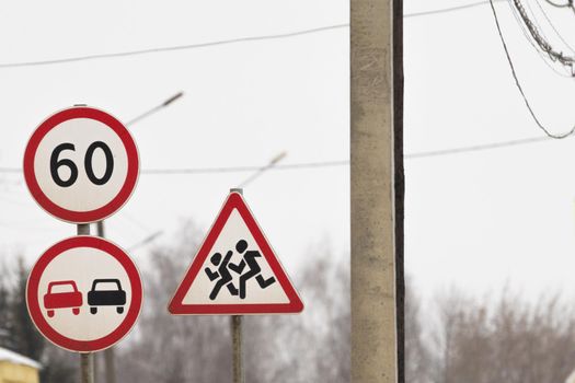 three road signs stand together. a sign overtaking is forbidden, the speed restriction sign. sign caution children. prohibition and warning signs for cars