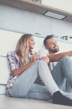 close up. young couple drinking coffee sitting on the kitchen floor