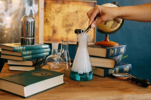 Schoolgirl perform chemical experiments. Flasks with solutions and chemical formulas on the blackboard in the school classroom. Back to school. School and preschool education.