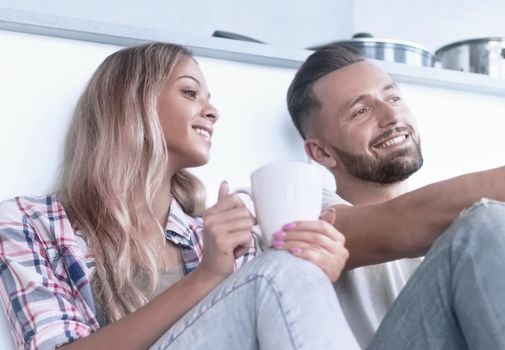 close up. young couple drinking coffee sitting on the kitchen floor