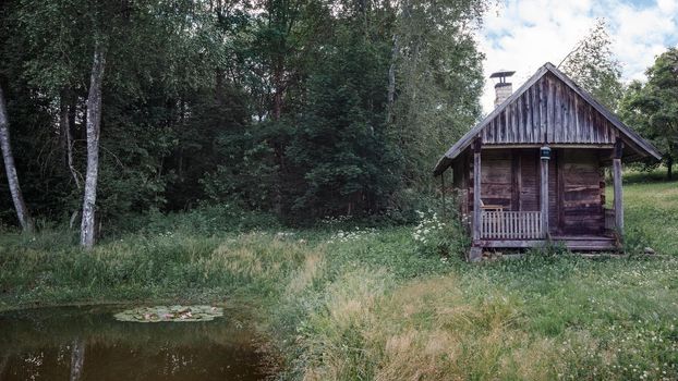 Village sauna house next to the forest and a pond.