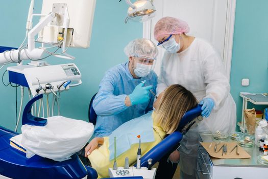 A female patient in dental glasses treats teeth at the dentist with ultraviolet light. dental fillings.