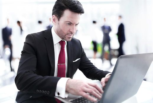 Businessman typing on a laptop, sitting at his Desk.photo with copy space