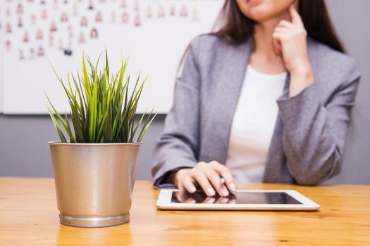 A brunette businesswoman in a gray jacket at her desk with a tablet in her hands. Business portrait in the office.