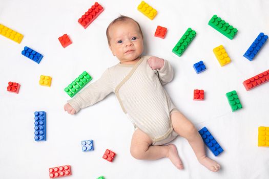 The baby is lying in toys . An article about children's toys. A selection of toys for kids. Designer