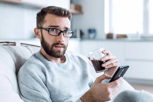 close up. a young man with a smartphone sitting in a comfortable chair. photo with copy space