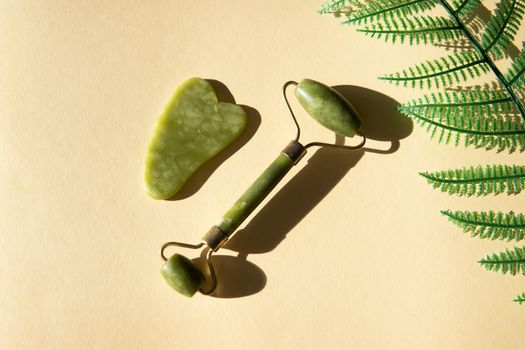 Jade Gua sha scraper and facial massager on beige background. Hard light, shadows, the concept self-care. Facial care. Zero waste. Lifting and toning treatment at home.