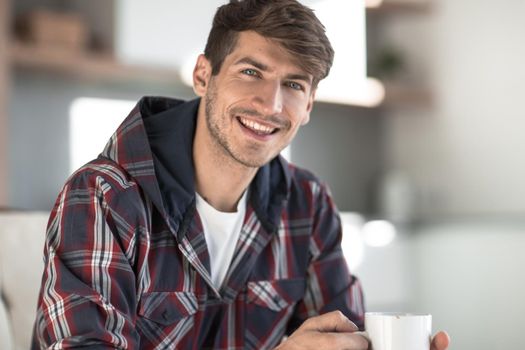 close up. young man with a Cup of coffee in the background in the kitchen