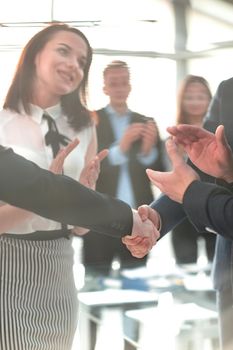 Handshake in front of business people in the bright modern office