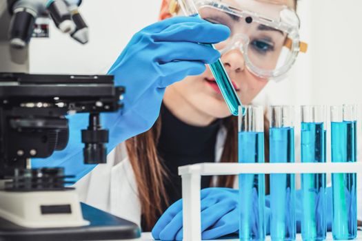 Young woman scientist working in chemical laboratory and examining biochemistry lab sample. Science technology medicine research and development study concept.