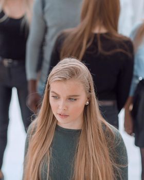 image of a serious woman standing in front of a casual group of young people.